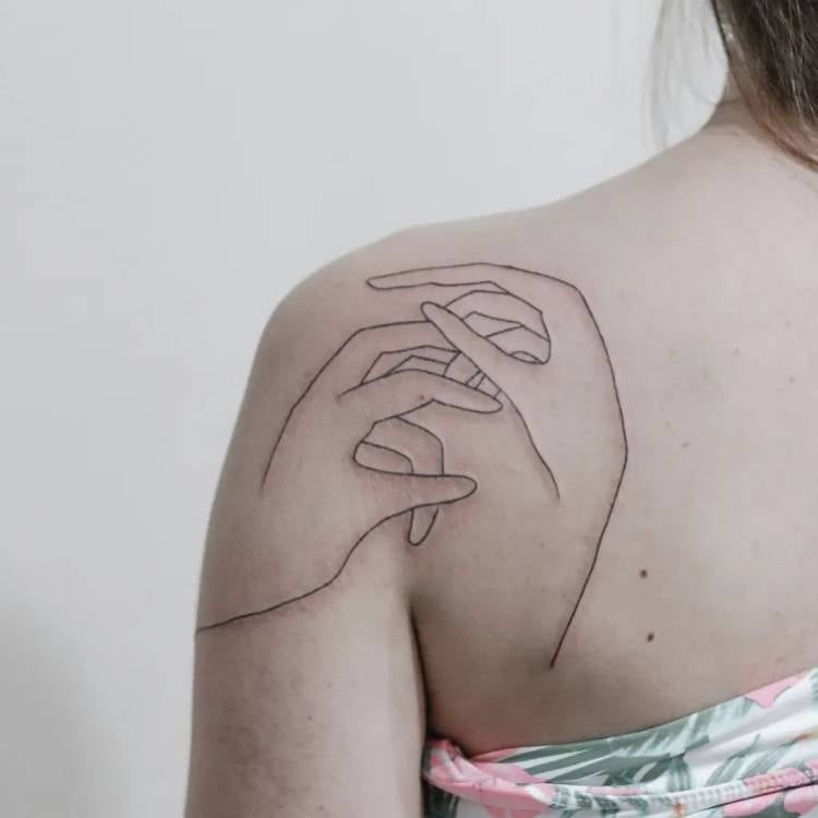 Mulher de pele clara de costas com tatuagem fine line de duas mãos