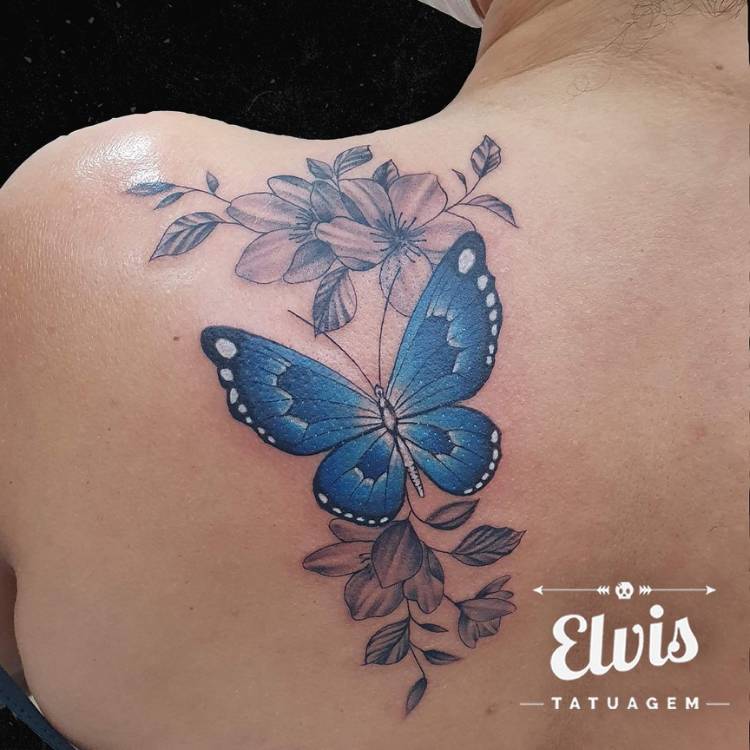 Mulher de pele clara de costas com tatuagem grande de borboleta azul com várias flores em preto