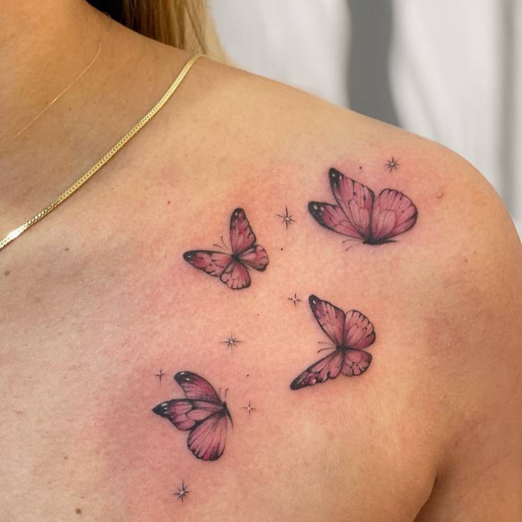 Mulher de pele clara com ombro tatuado com 4 borboletas rosas