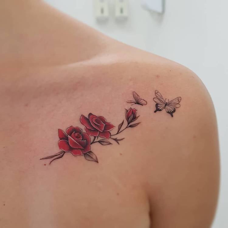 Mulher de pele clara com tatuagem de rosas vermelhas e borboletas delicadas no ombro