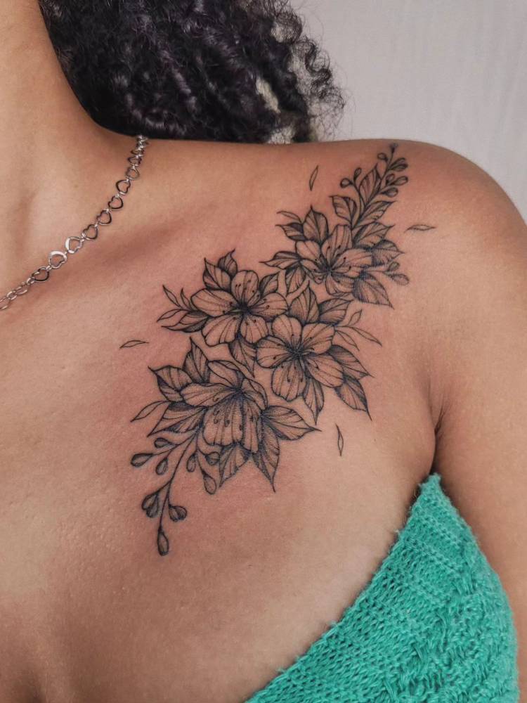 Mulher de pele morena com tatuagem de flores no ombro