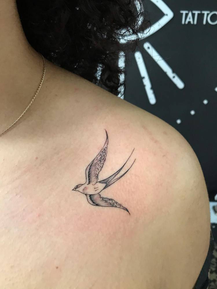 Mulher de pele clara com pássaro sombreado tatuado no ombro