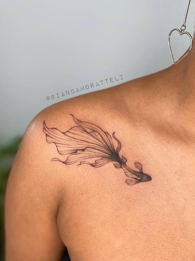 Mulher de pele morena com peixe fine line sombreado tatuado no ombro