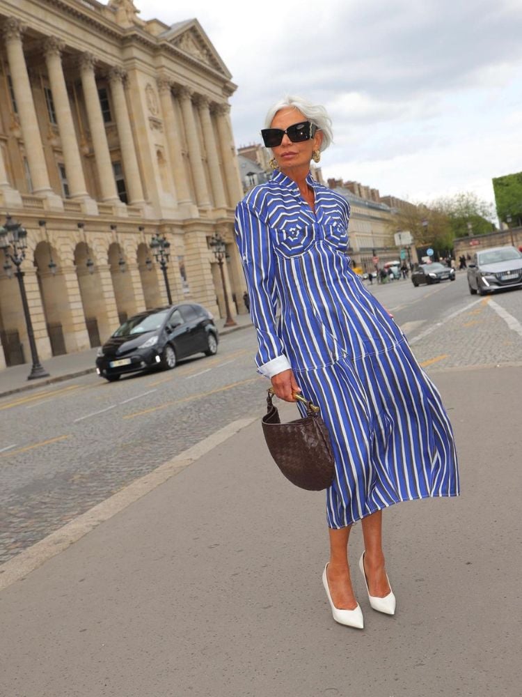 Influencer Grece Ghanem usando vestido mídi azul listrado com bolsa marrom e sapato scarpin branco