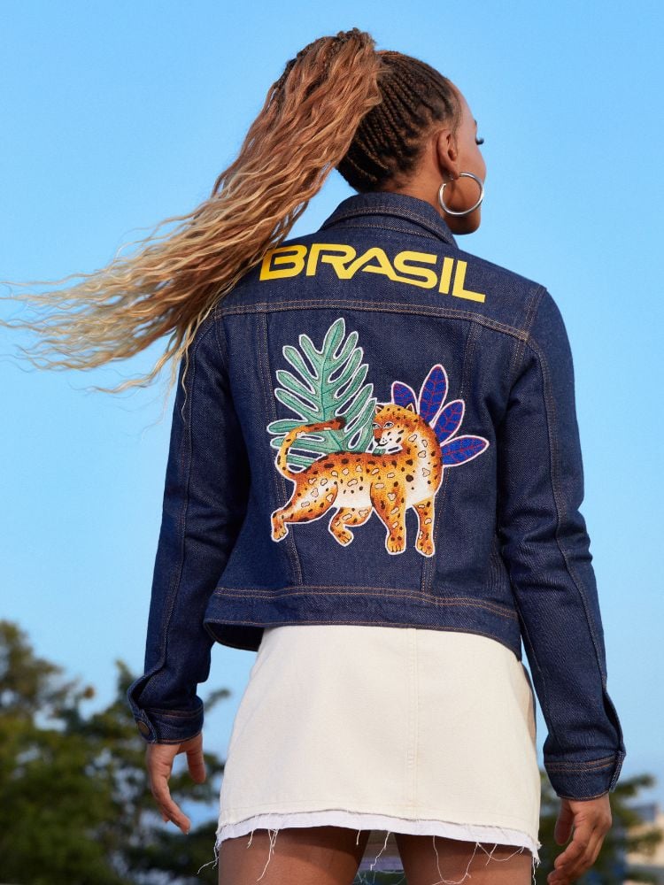 Ginasta Rebeca Andrade usando uniforme da Riachuelo para as Olimpíadas de Paris: jaqueta jeans e saia branca