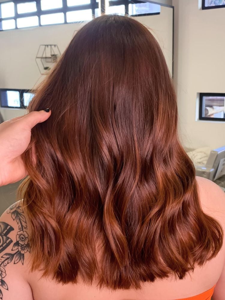 foto de mulher usando um dos tons de cabelo ruivo que é tendência, o ruivo quente