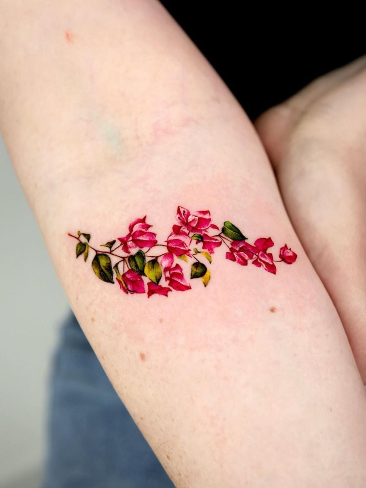 braço com tatuagem de flor primavera, nas cores rosa e verde