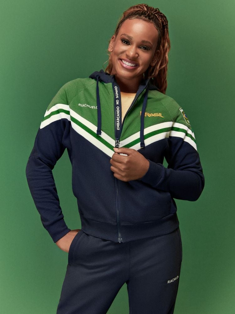 Ginasta Rebeca Andrade usando uniforme da Riachuelo para as Olimpíadas de Paris: jaqueta azul, verde e branca com calça azul