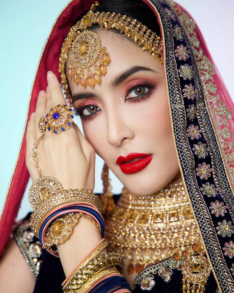 Mulher com roupa indiana vermelha e dourada e make rosa com batom vermelho