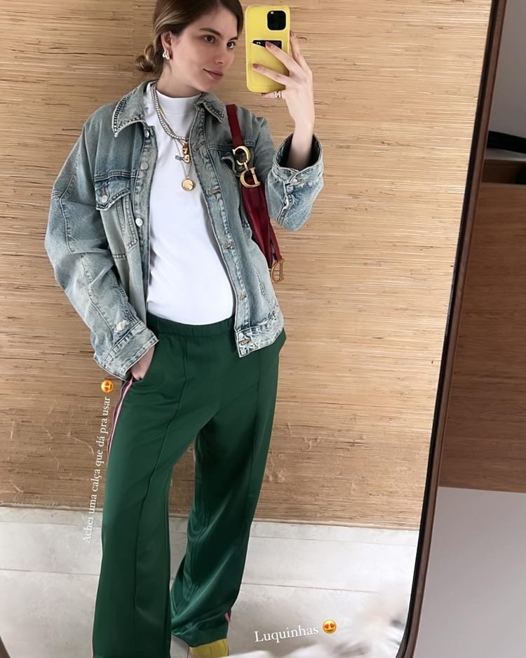 Atriz Bruna Hamú grávida de calça verde, jaqueta jeans e blusa branca em foto no espelho