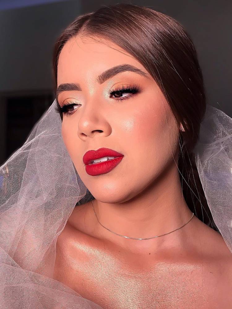 Mulher de pele clara usando véu, sombra clara nos olhos e batom vermelho nos lábios