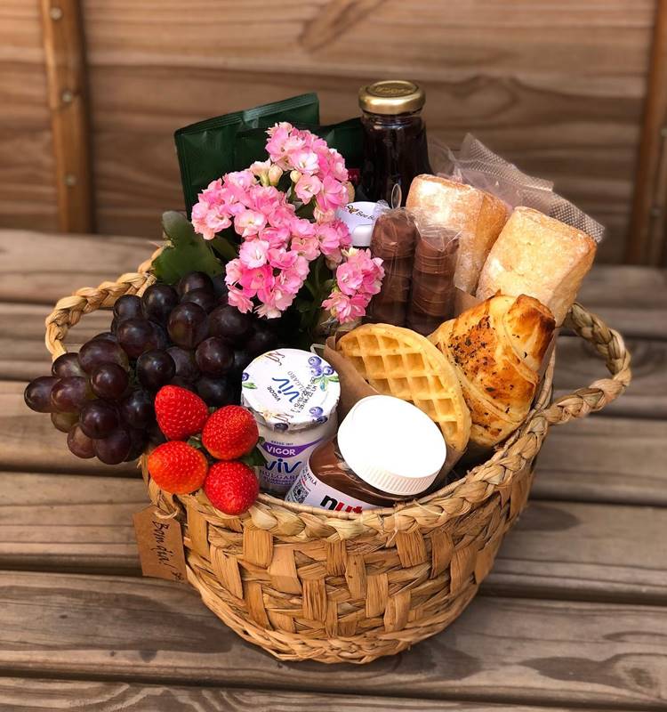cesta de café da manhã com pães, frutas e flores