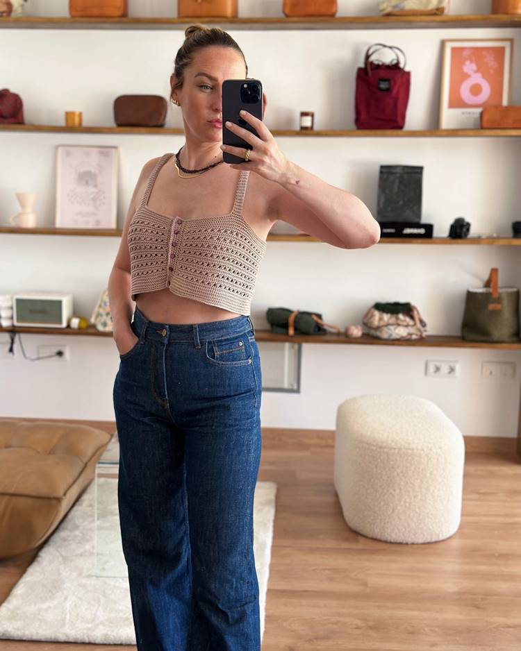 Mulher usando cropped de crochê bege com botões e calça jeans