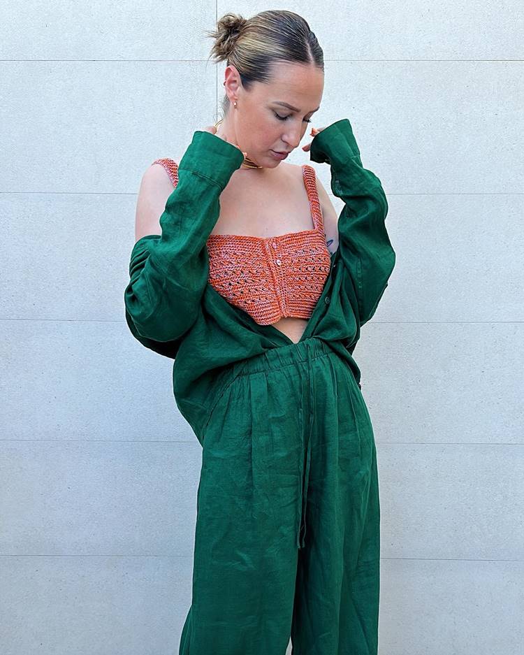 Mulher usando cropped de crochê laranja com botões e conjunto de calça e camisa verdes