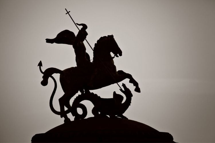 Foto de sombra de São Jorge sobre cavalo apontando lança para um dragão