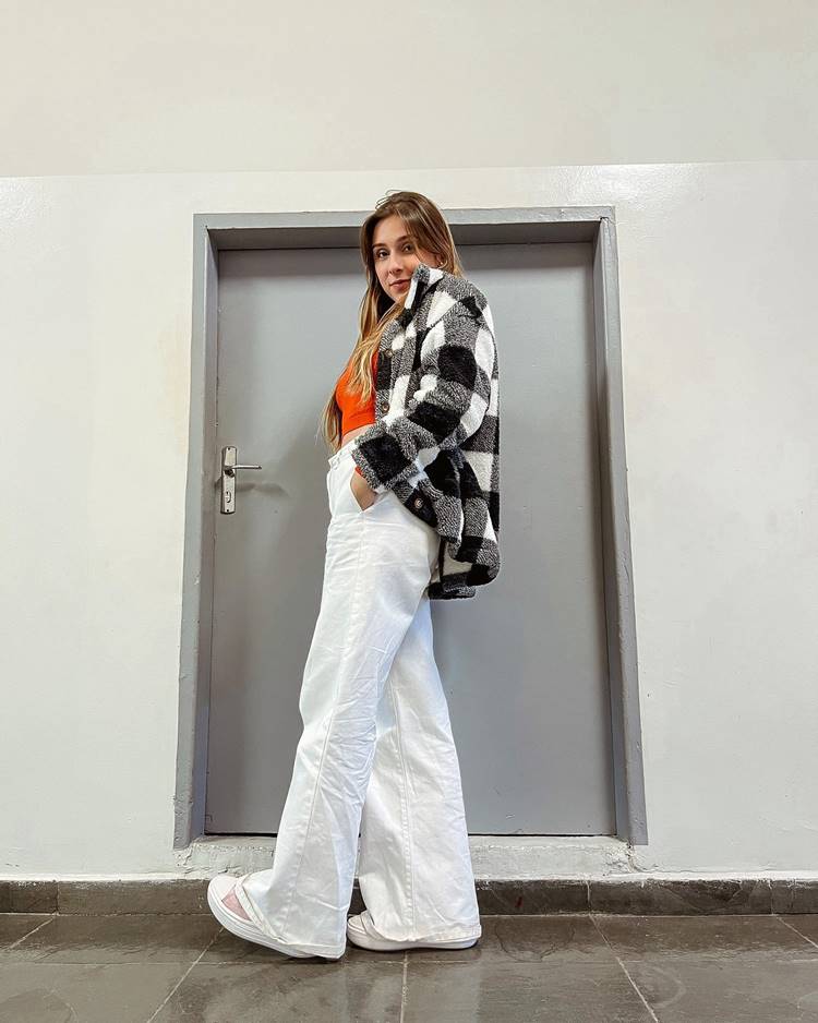 Menina com look junino: calça branca, cropped laranja e casaco xadrez