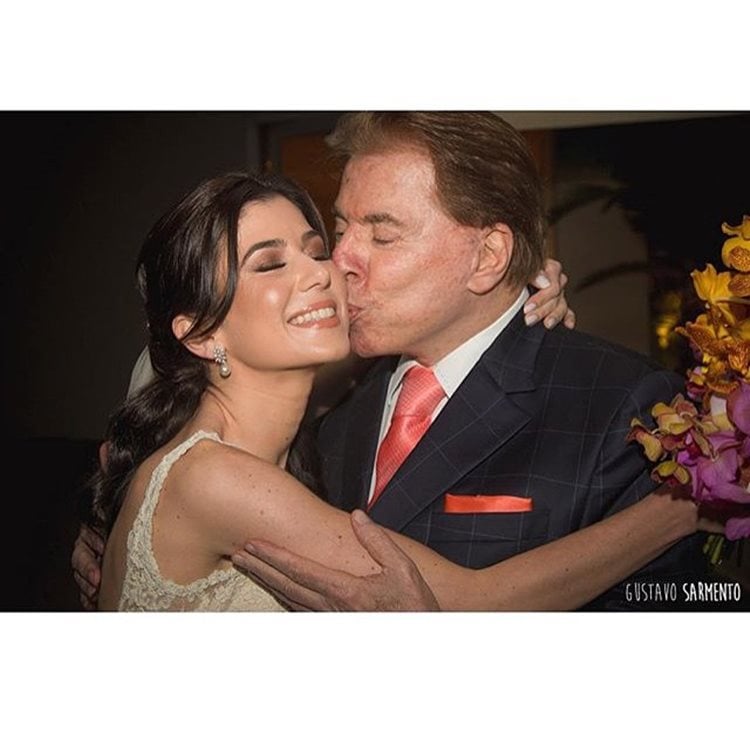 Renata Abravanel de noiva em seu casamento recebendo um beijo no rosto de seu pai, Silvio Santos