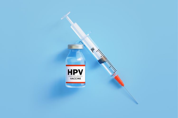Fundo azul com frasco de vacina escrito "HPV vaccine" e seringa com agulha