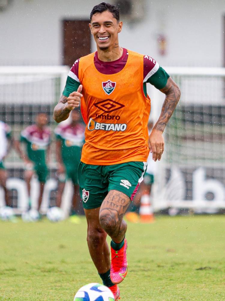 Jogador Vitor Mendes com uniforme do Fluminense e colete laranja 