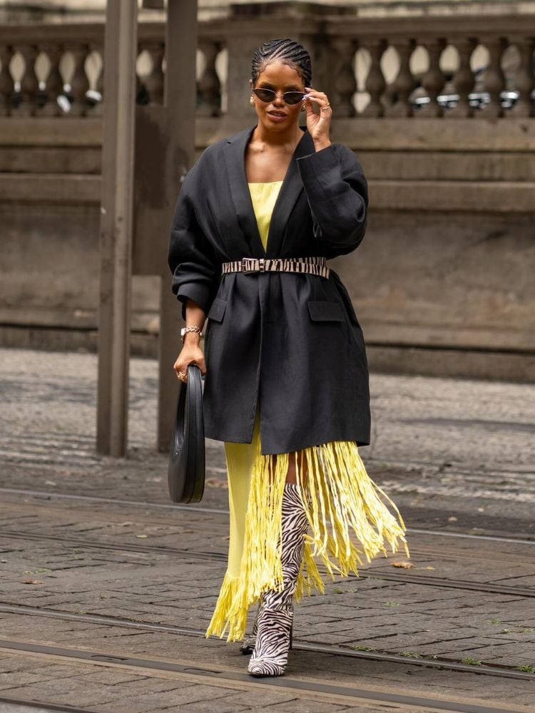 mulher usando blazer oversized e saia com franjas amarelas