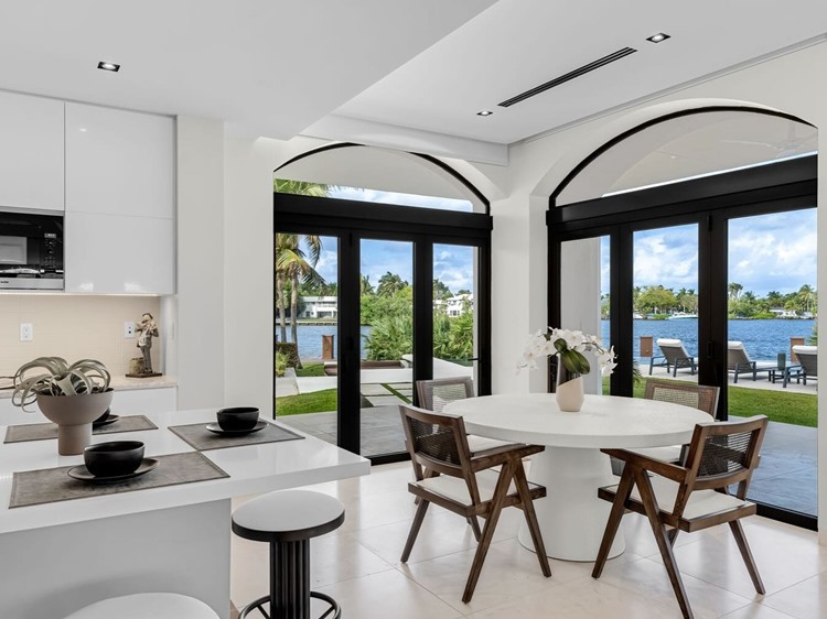 Nova mansão de Gusttavo Lima vista por dentro, cozinha com mesa redonda, ilha e vista para mar do lado de fora