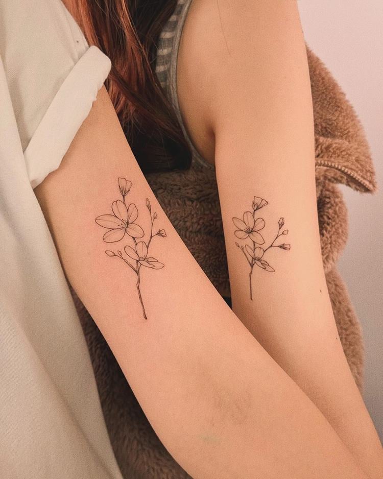 Tatuagem delicada de ramo de flor orquídea em braço, próximo do pulso, em dois braços