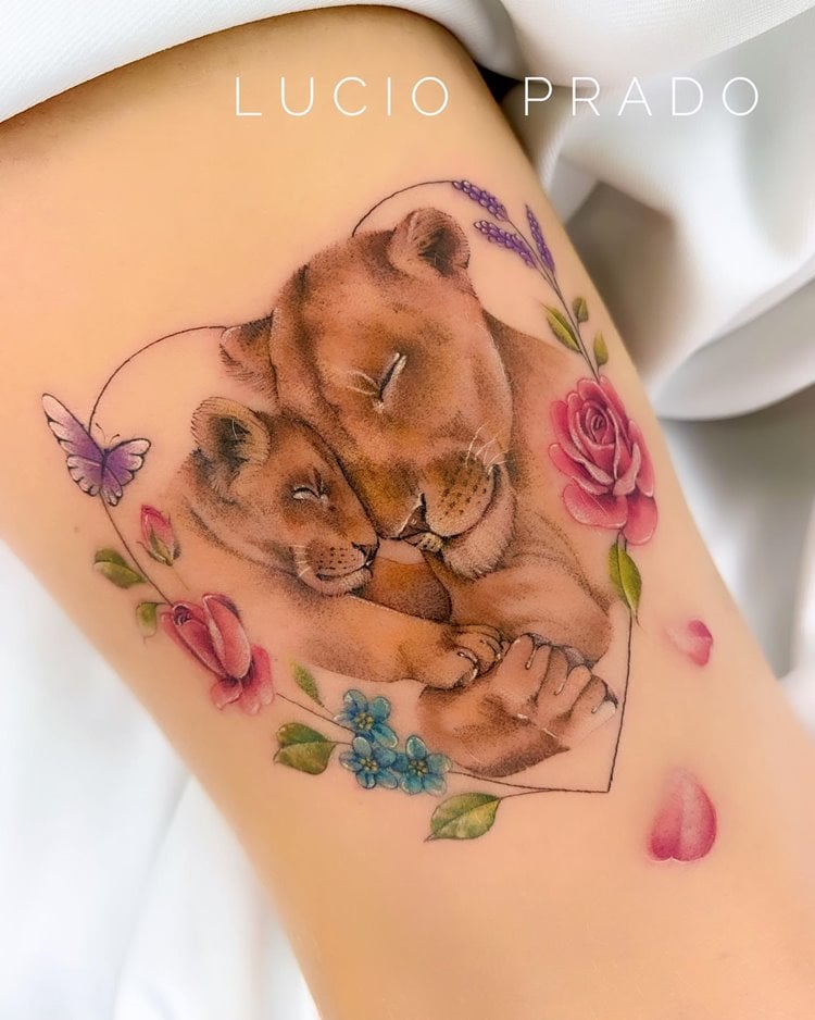 Tatuagem leoa e filhote com flores em um coração coloridas