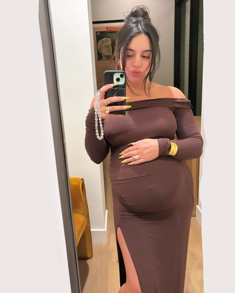 Atriz Vanessa Hudgens de High School Musical grávida em 2024 usando vestido marrom de fenda em foto no espelho