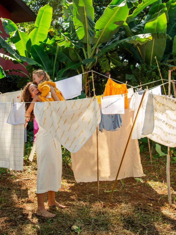 Foto de campanha da collab Fábula e Mana mostra mãe e filha criança em meio a varal de roupas
