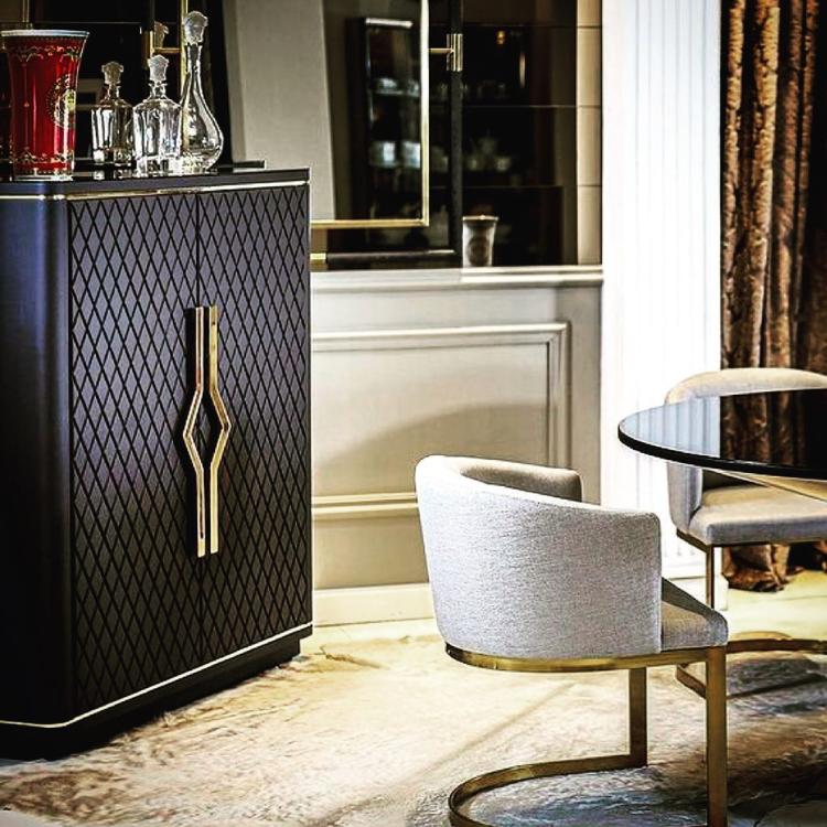 Móvel bar revestido em couro natural preto em sala com mesa e cadeiras redondas em off white