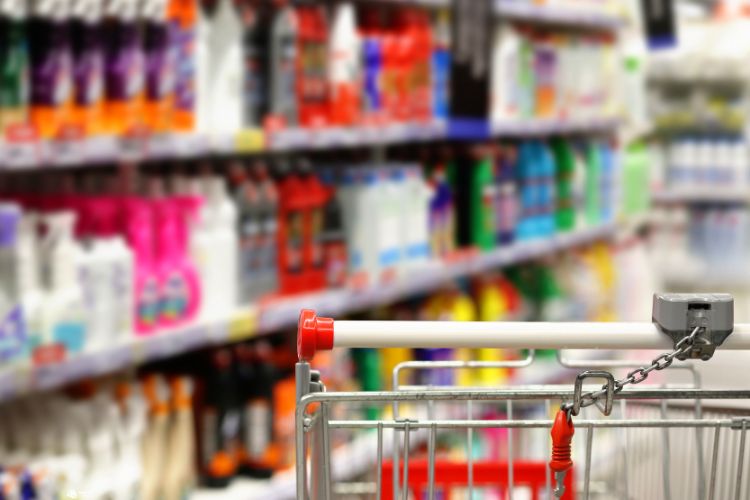 Imagem de carrinho de supermercado com produtos de limpeza ao fundo