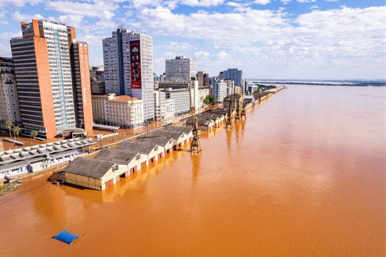 Foto aérea do Cais Mauá alagado, com água marrom cobrindo casas e ruas