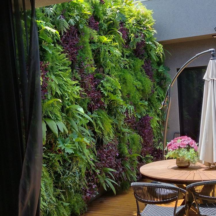Parede verde com plantas roxas também em área externa com mesa 