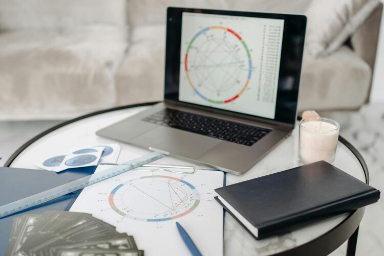 Mesa com notebook, e um mapa astral sendo analisado