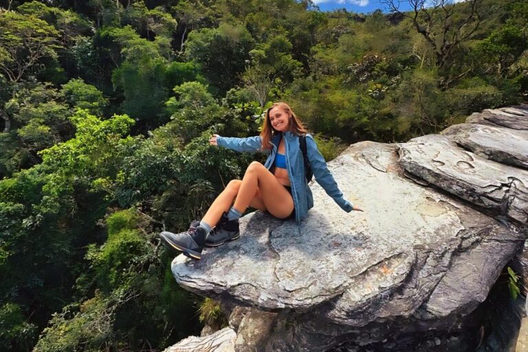 Foto de mulher sentada em pedra após fazer trilha, no Parque Estadual de Ibitipoca