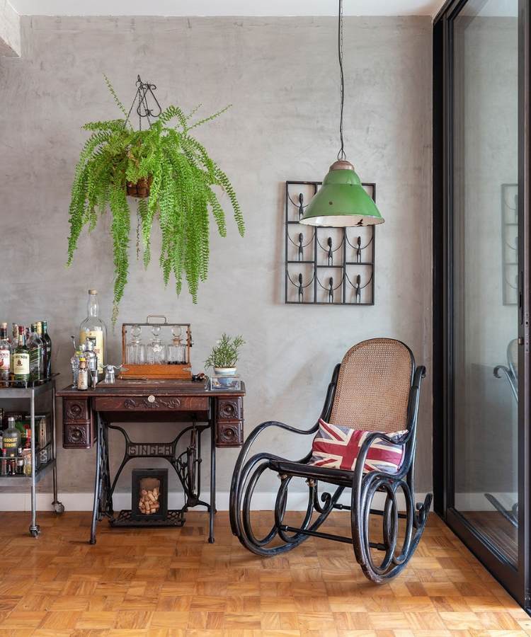 Ambiente de casa com bar, cadeira de balanço, luminária verde e planta samambaia