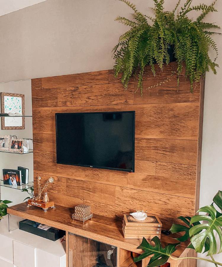Painel de TV de madeira com decorações, plantas e uma samambaia