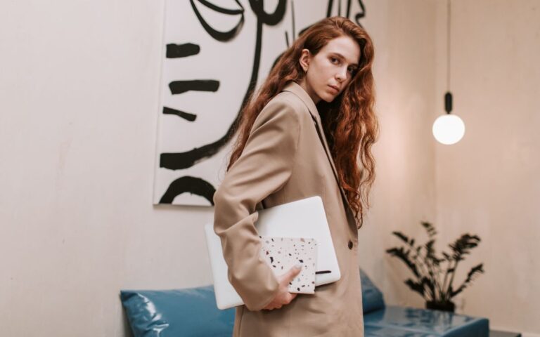Mulher usando blazer marrom e segurando notebook, tendências femininas em 2024