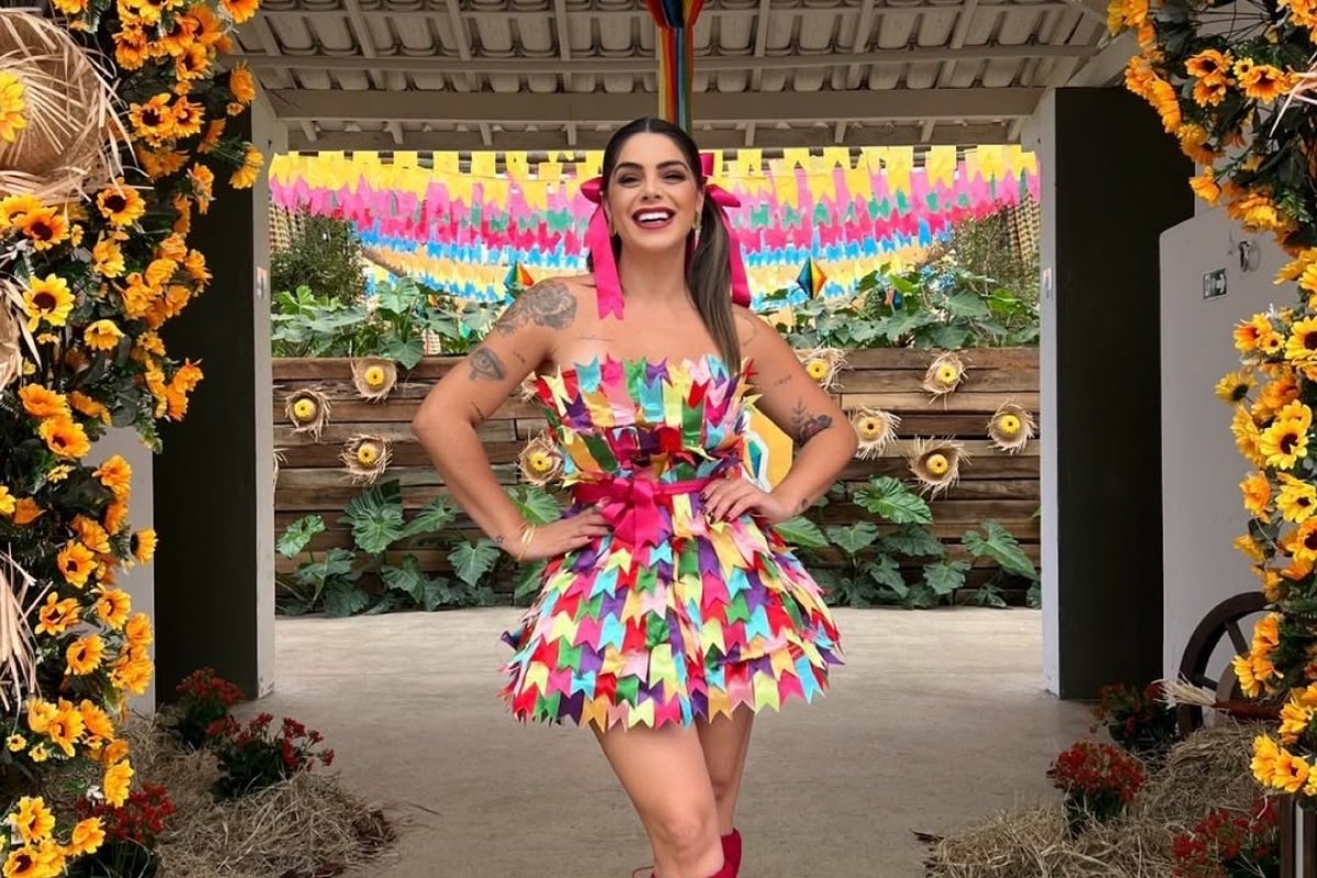 Mulher de pele clara na festa junina com look de vestido de bandeirinhas coloridas