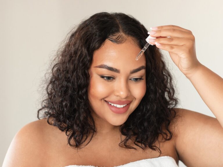 Mulher plus size aplicando retinol em conta-gotas no rosto
