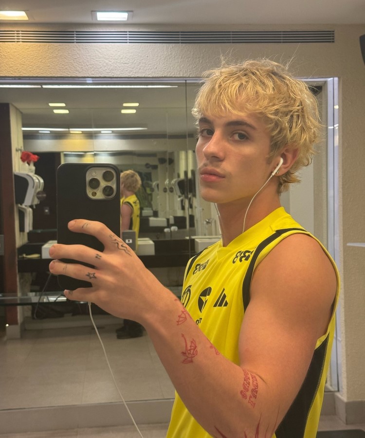 o influencer em selfie no espelho em um banheiro público, usando regata amarela e preta