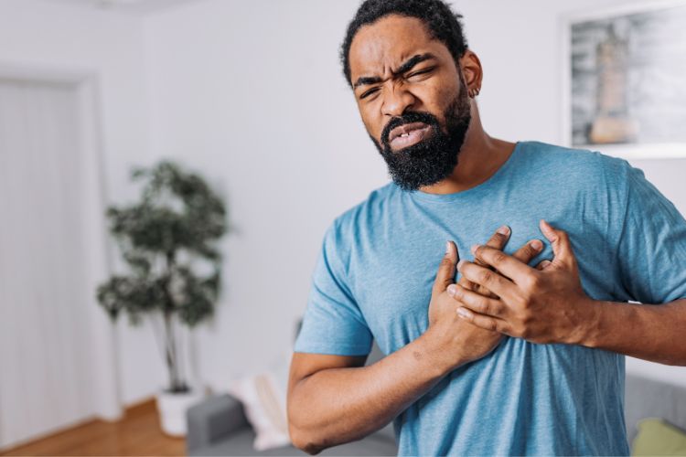 Homem negro com as mãos no peito, porque está com dor no peito