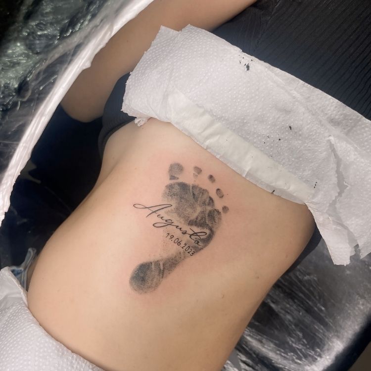 Costela de pessoa de pele clara com carimbo do pé e nome do filho "Augusto"