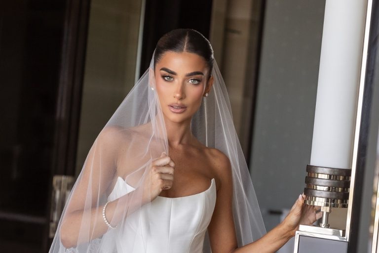 Mulher de pele clara de noiva com maquiagem nude, véu e coque