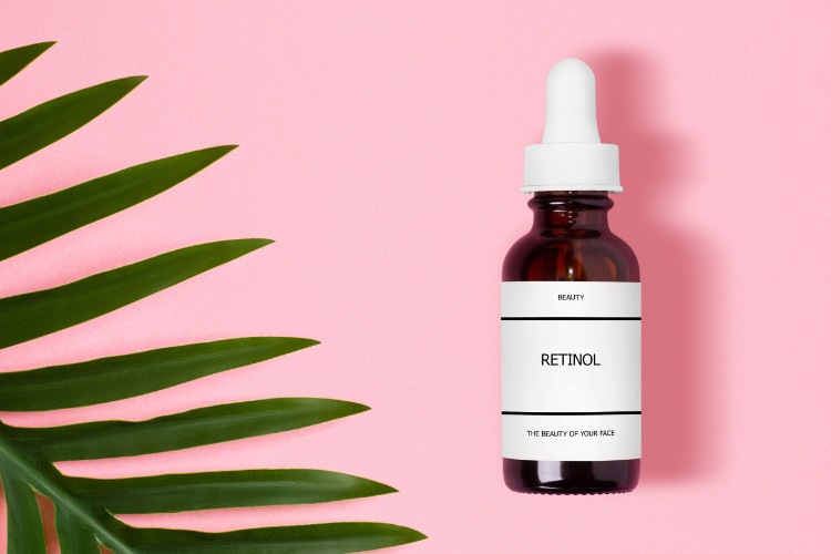 Produto retinol em frasco de conta-gotas em fundo rosa com folha verde