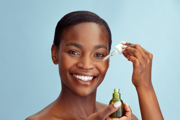 mulher negra segurando conta-gotas com retinol