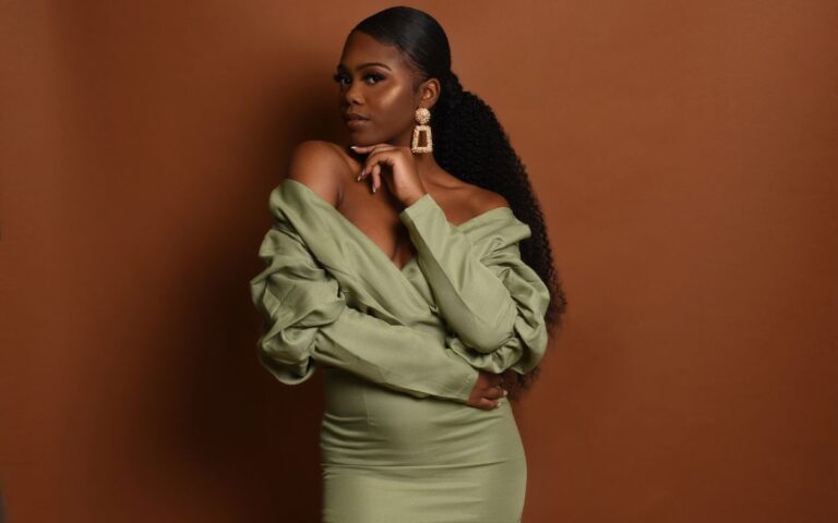 Foto de mulher negra de rabo de cavalo, maxi brinco e vestido de manga longa verde