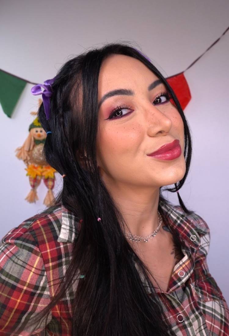 Maquiadora Ana Veiga com make para festa junina. Ela usa camiseta xadrez vermelha