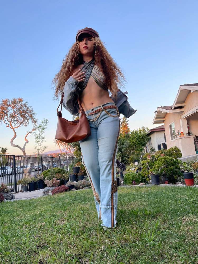 Mulher de pele morena usando cropped, calça cintura baixa jeans, boné