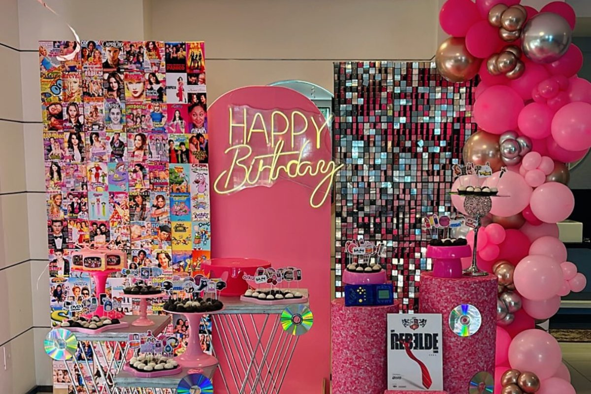 Decoração de festa anos 2000 com posteres de cantores da década, balões metalizados, CDs e mais